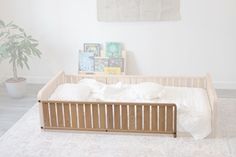 a baby crib in the corner of a room with a potted plant and pictures on the wall