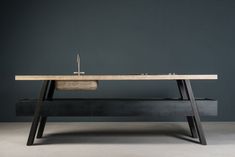 a wooden table with two sinks on it in front of a gray wall and grey floor