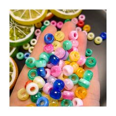 a hand is full of colorful beads and lemons next to some sliced oranges