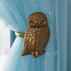 an owl figurine hanging on the curtain in front of a blue drapes