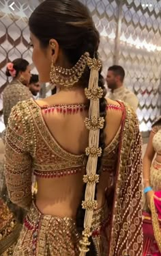 the back of a woman's dress with gold and red jewelry on her neck