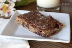 a white plate topped with chocolate chip bars next to a glass of milk and flowers