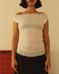 a woman wearing a white sweater and black skirt standing in front of a red wall