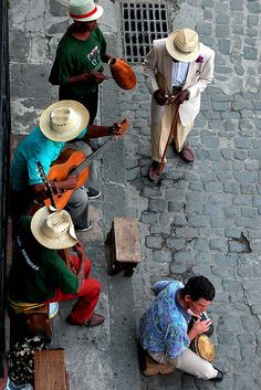 three men are sitting on the street playing instruments