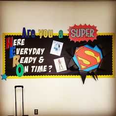 a bulletin board with some pictures on it and a suitcase in front of the sign that says, are you super here everyday ready & on time?