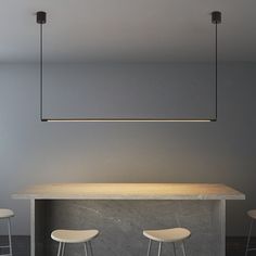 three stools sit at the end of a table with a light hanging above it