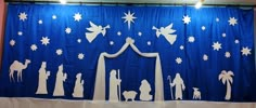 a blue curtain with white silhouettes of people and nativity scene