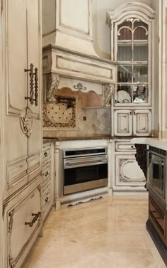 a kitchen with white cabinets and marble counter tops, an oven and microwave in the corner