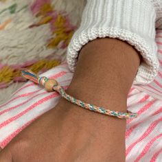 a person wearing a white and blue bracelet on their wrist with a wooden bead