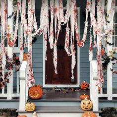 a porch decorated for halloween with pumpkins and icing hanging from the front door