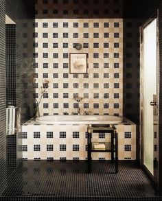 a bathroom with black and white tiles on the walls, flooring and bathtub