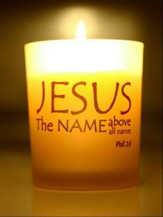 a lit candle with the name jesus on it