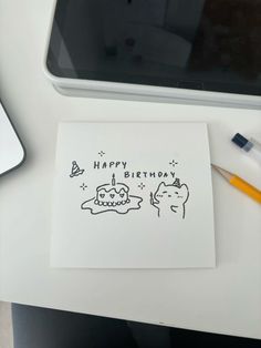 a happy birthday card sitting on top of a desk next to a laptop and pen