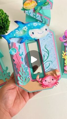 someone is holding up an origami house with dolphins and sea animals on it