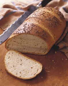 a loaf of bread sitting on top of a wooden cutting board next to a knife