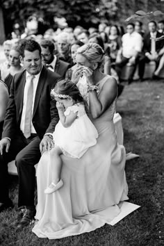 a woman in a white dress is holding a small child and sitting on a chair