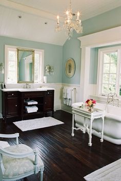 a large bathroom with wood floors and white fixtures, including a claw foot bathtub