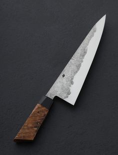 a large knife with a wooden handle on a black surface