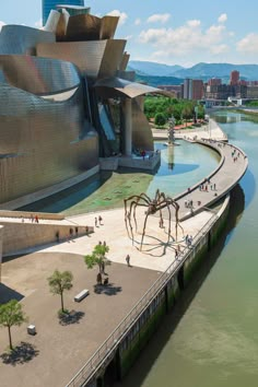 an aerial view of a large building next to a body of water with people walking around it