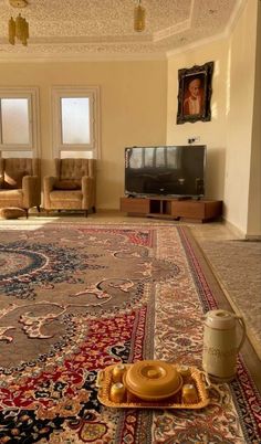 a living room filled with furniture and a large rug on the floor in front of a flat screen tv