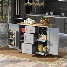 a kitchen with an island and lots of drawers on the counter top, in front of a potted plant