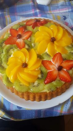 a fruit tart with kiwis, strawberries and oranges on it