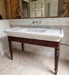 a bathroom sink sitting under a mirror in front of a counter top with two sinks underneath it