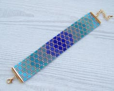 a blue beaded bracelet on a wooden surface with gold chains and clasps hanging from it