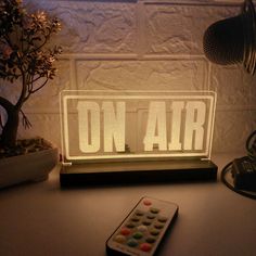 a remote control sitting on top of a table next to a light that reads on air