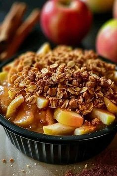 an apple crisp in a bowl with granola on top and apples in the background