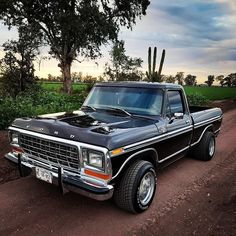 an old pickup truck parked on a dirt road