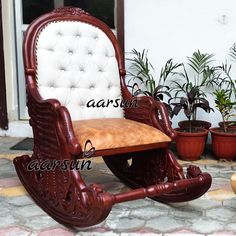 a wooden rocking chair sitting on top of a stone floor next to potted plants