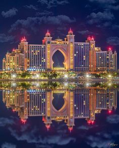 an image of a city at night with lights on it's buildings and the reflection in the water