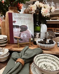 a table topped with plates and wine glasses next to a book on top of a wooden board