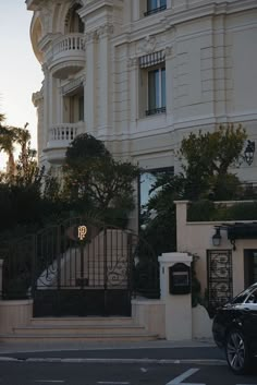 a black car parked in front of a tall white building with a clock on it's side