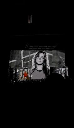 a woman is standing in front of a television screen with her face on the screen