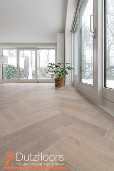 an empty room with wooden floors and large windows