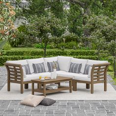 an outdoor patio furniture set with pillows on the floor and table in front of it