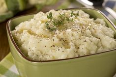 a green bowl filled with mashed potatoes on top of a table