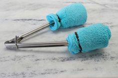 two blue towels are attached to the handles of some kitchen utensils on a marble counter