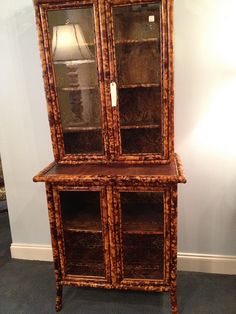 an old wooden china cabinet with glass doors and drawers on the front, sitting against a wall