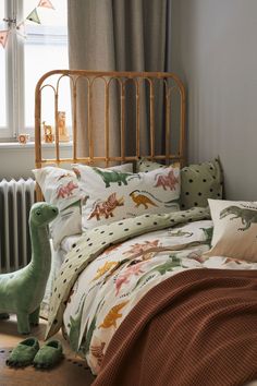 a bed with dinosaurs on it next to a radiator and window sill