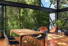 an outdoor dining area with wooden floors and large glass doors leading to the trees outside