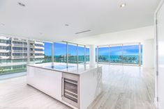 an empty kitchen with large windows overlooking the ocean