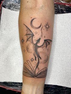 a tattoo on the leg of a person with an open book in front of them