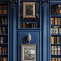 the bookshelves are blue and there is a lamp in front of them on the wall