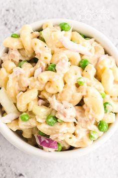 a white bowl filled with macaroni salad and peas