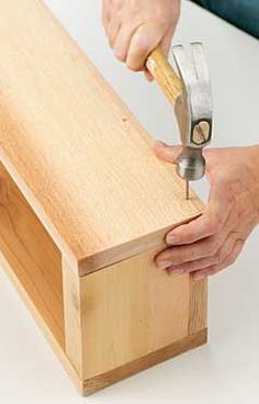 a person using a pair of pliers to attach a piece of wood on top of a table