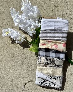 a bunch of cloths sitting on top of a cement floor next to white flowers