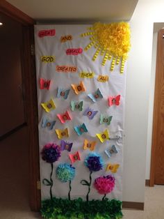 a bulletin board with paper flowers and butterflies on it, next to a hallway door